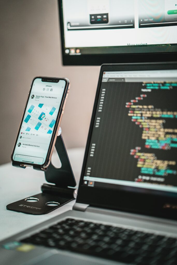Bild zeigt mobile Device mit geöffneter App und daneben ein Laptop mit Code